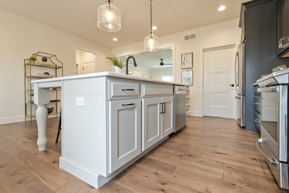 Eat-in kitchen - transitional single-wall light wood floor and brown floor eat-in kitchen idea with an undermount sink, raised-panel cabinets, dark wood cabinets, quartz countertops, white backsplash, brick backsplash, stainless steel appliances, an island and white countertops