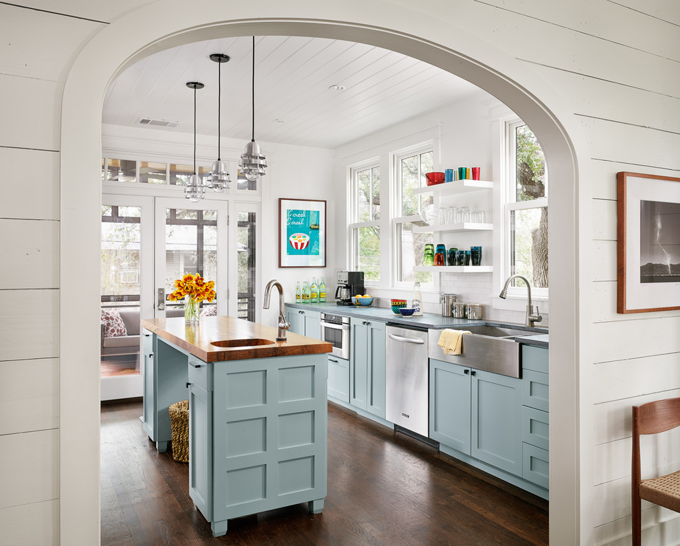 Inspiration for a farmhouse galley enclosed kitchen remodel in Austin with a farmhouse sink, shaker cabinets, blue cabinets, white backsplash and stainless steel appliances