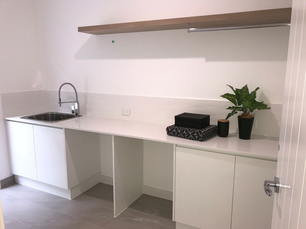 Mid-sized contemporary single-wall utility room in Brisbane with a drop-in sink, open cabinets, dark wood cabinets, granite benchtops, yellow walls, porcelain floors, a concealed washer and dryer and grey floor.