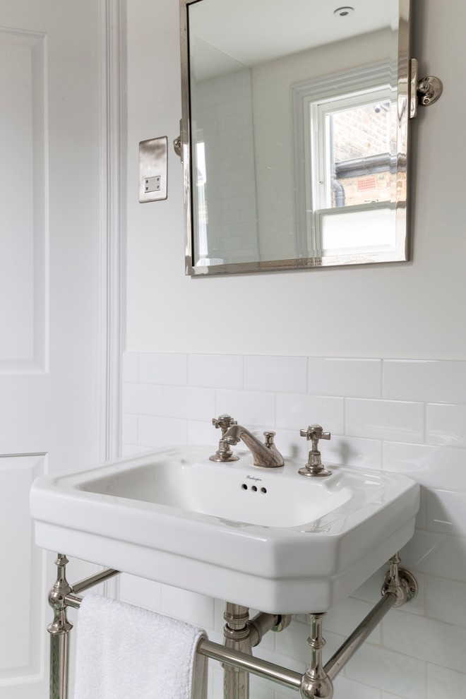 This is an example of a mid-sized transitional bathroom in London with a drop-in tub, an open shower, a two-piece toilet, blue tile, white tile, cement tile, white walls, ceramic floors and a pedestal sink.
