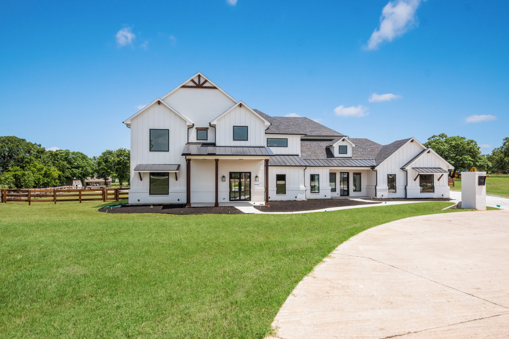 Photo of a large and white rural two floor detached house in Dallas with mixed cladding, a pitched roof, a mixed material roof, a black roof and board and batten cladding.