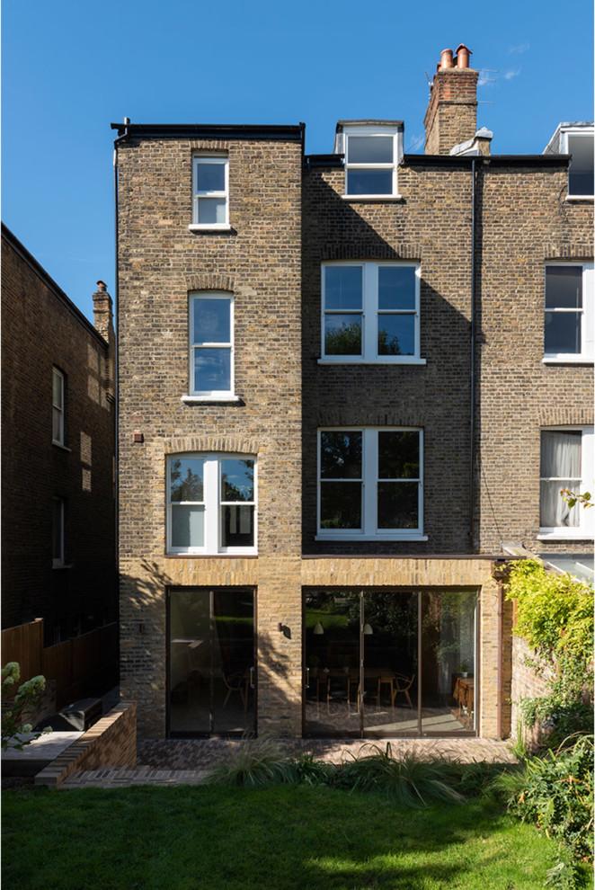 Large modern three-storey brick yellow duplex exterior in London with a flat roof and a mixed roof.