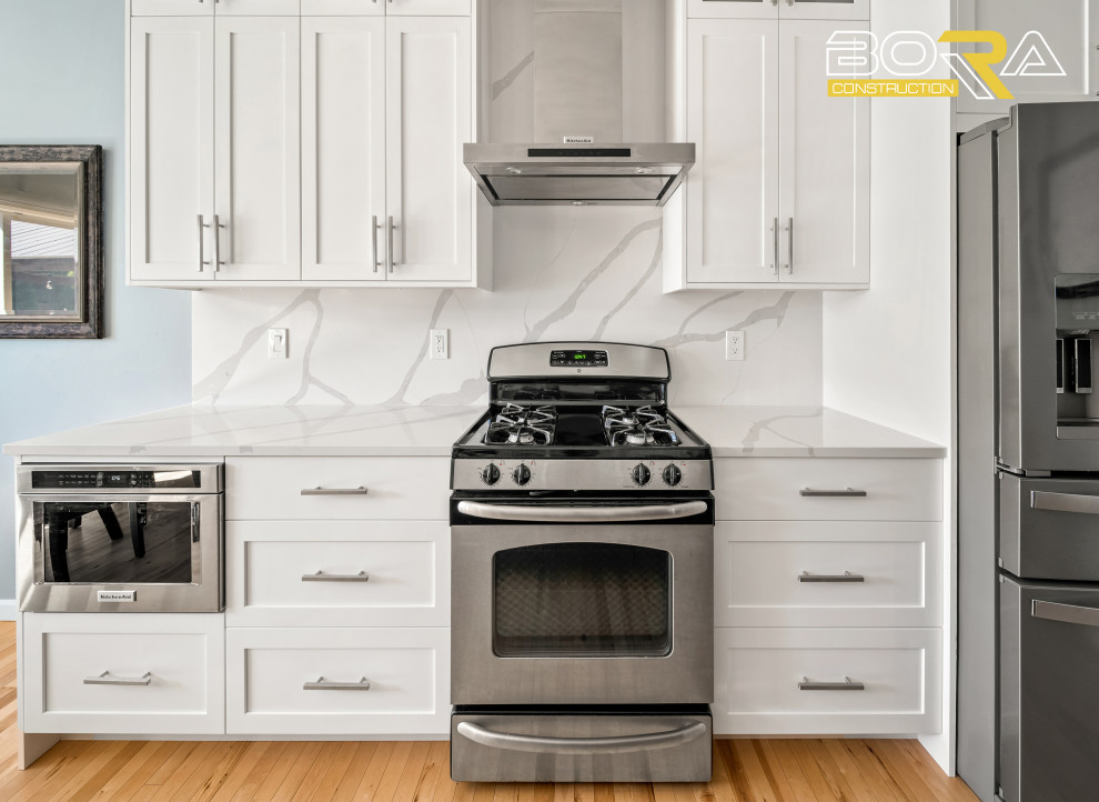 Eat-in kitchen - mid-sized single-wall light wood floor and brown floor eat-in kitchen idea in Seattle with a farmhouse sink, shaker cabinets, white cabinets, quartz countertops, white backsplash, quartz backsplash, stainless steel appliances, an island and white countertops