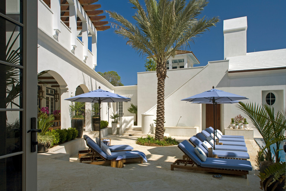 Photo of an expansive mediterranean courtyard patio in Miami with a water feature, natural stone pavers and a pergola.