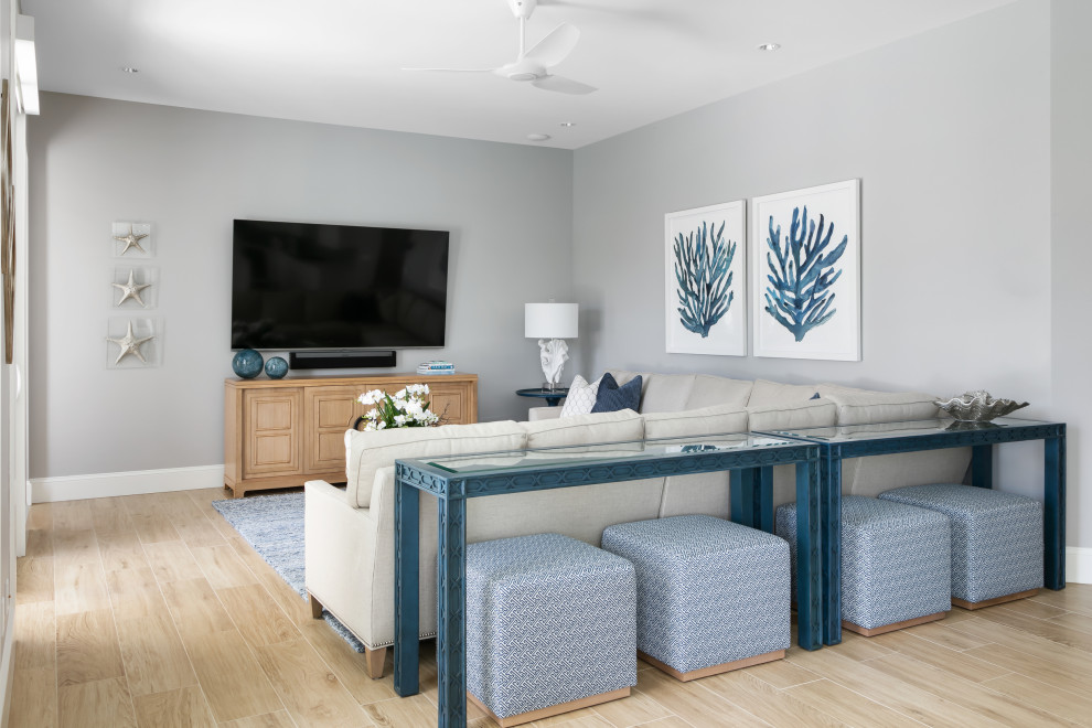 Photo of a mid-sized beach style open concept family room in Tampa with grey walls, porcelain floors, a wall-mounted tv, brown floor and no fireplace.