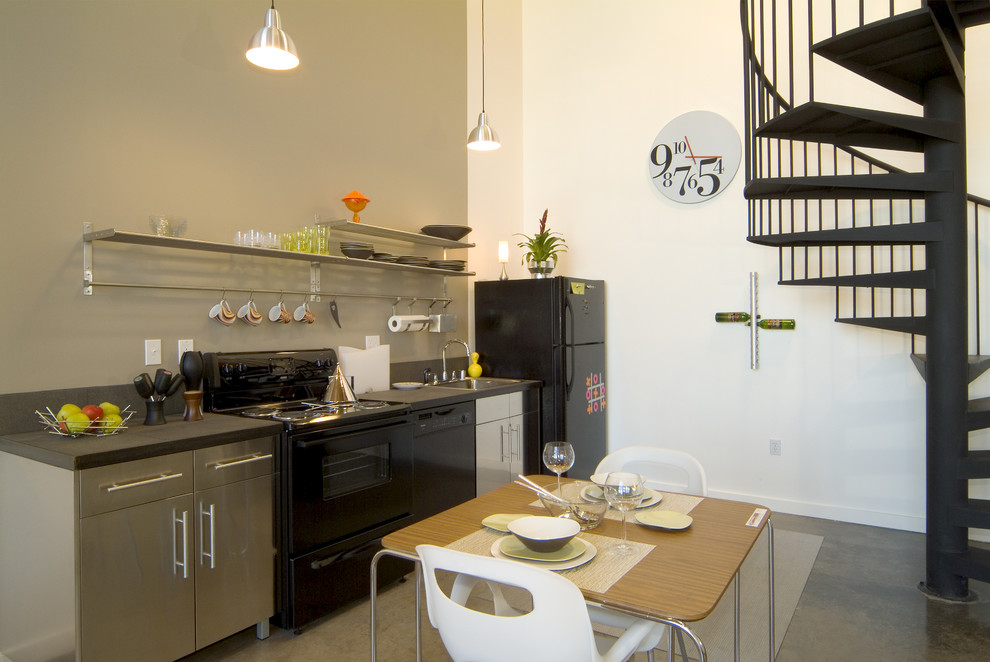 Inspiration for a modern single-wall eat-in kitchen in Sacramento with black appliances, flat-panel cabinets, stainless steel cabinets, a drop-in sink, solid surface benchtops, concrete floors and no island.