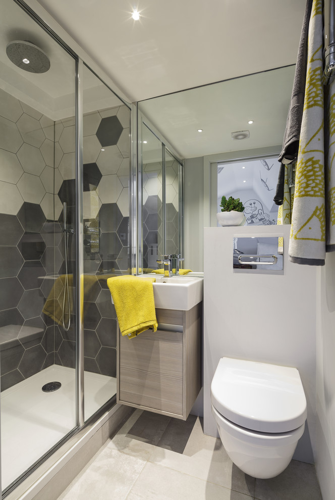 This is an example of a small eclectic master bathroom in London with flat-panel cabinets, light wood cabinets, a freestanding tub, an open shower, a wall-mount toilet, multi-coloured tile, cement tile, grey walls, ceramic floors, a trough sink, grey floor, a sliding shower screen and white benchtops.