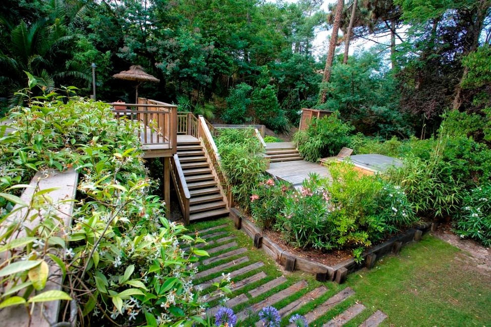 This is an example of a large tropical backyard deck in Bordeaux with a container garden and no cover.