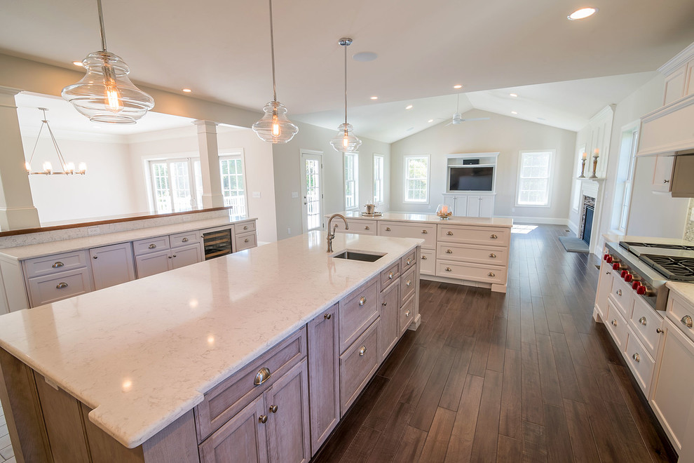 Inspiration for a huge transitional l-shaped medium tone wood floor kitchen pantry remodel in Providence with white cabinets, granite countertops, beige backsplash, stone tile backsplash, white appliances, a farmhouse sink, recessed-panel cabinets and two islands