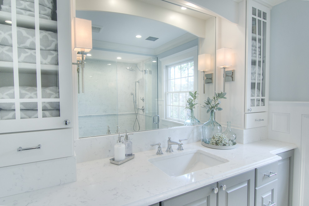 Photo of a large transitional kids bathroom in Other with raised-panel cabinets, grey cabinets, a curbless shower, a two-piece toilet, white tile, porcelain tile, blue walls, marble floors, an undermount sink, engineered quartz benchtops, white floor, a hinged shower door and white benchtops.