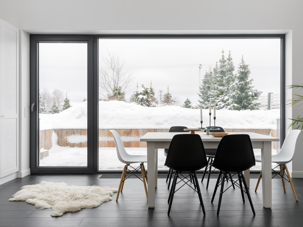 На фото: гостиная-столовая среднего размера в скандинавском стиле с белыми стенами, полом из керамогранита, стандартным камином, фасадом камина из металла, черным полом, балками на потолке и обоями на стенах
