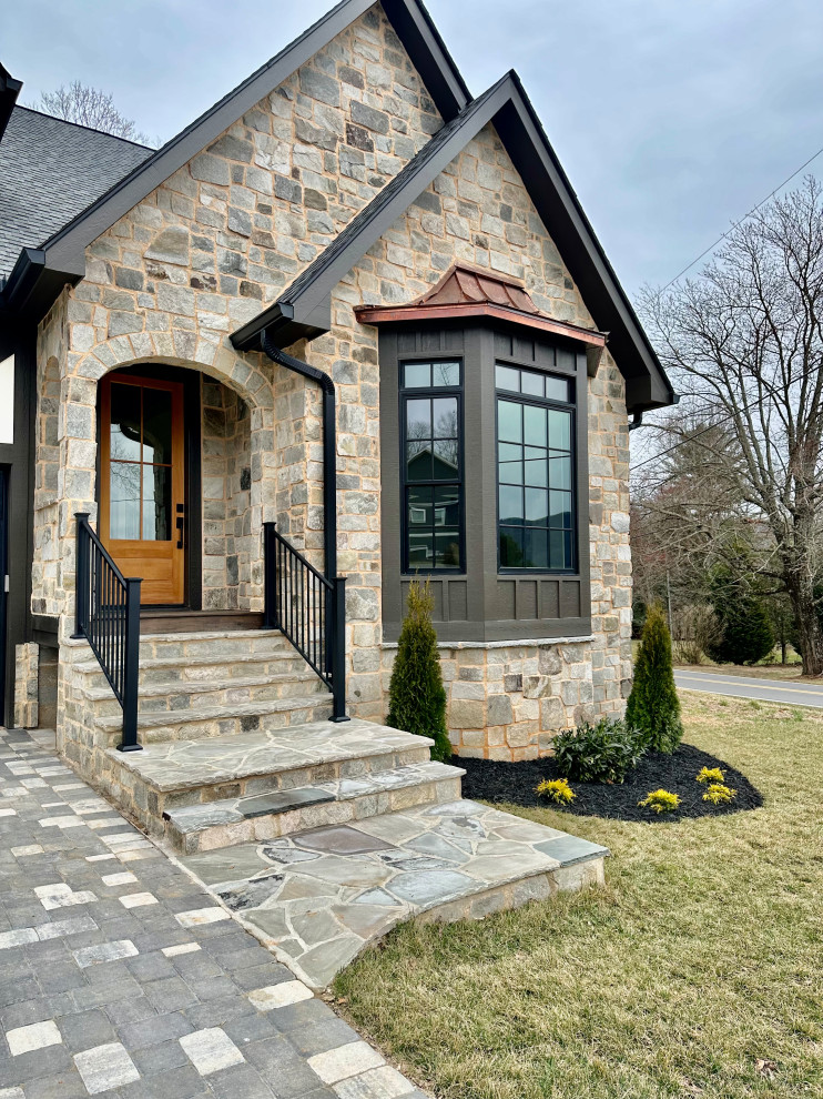 This is an example of a mid-sized two-storey white house exterior in Other with stone veneer, a gable roof, a shingle roof, a grey roof and board and batten siding.