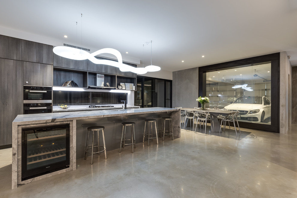 Photo of a mid-sized industrial galley open plan kitchen in Brisbane with an undermount sink, beaded inset cabinets, medium wood cabinets, marble benchtops, glass sheet splashback, black appliances, concrete floors, with island and beige floor.