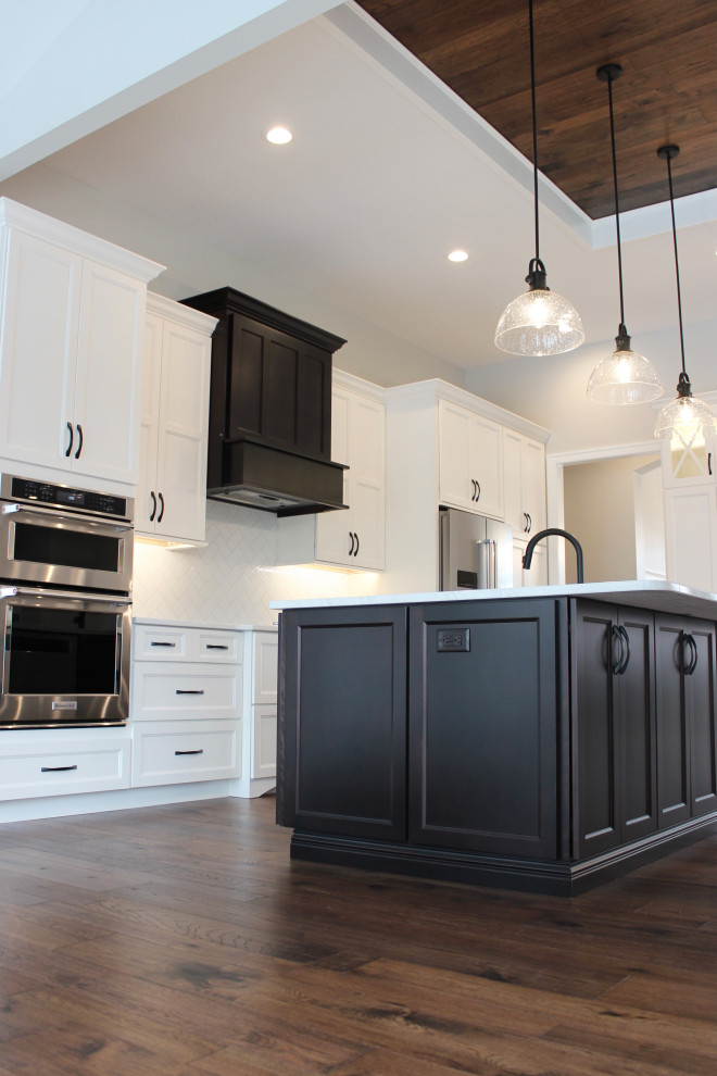 Exempel på ett mycket stort klassiskt vit vitt kök med öppen planlösning, med en undermonterad diskho, släta luckor, vita skåp, bänkskiva i kvarts, vitt stänkskydd, stänkskydd i tunnelbanekakel, rostfria vitvaror, mellanmörkt trägolv, en köksö och brunt golv