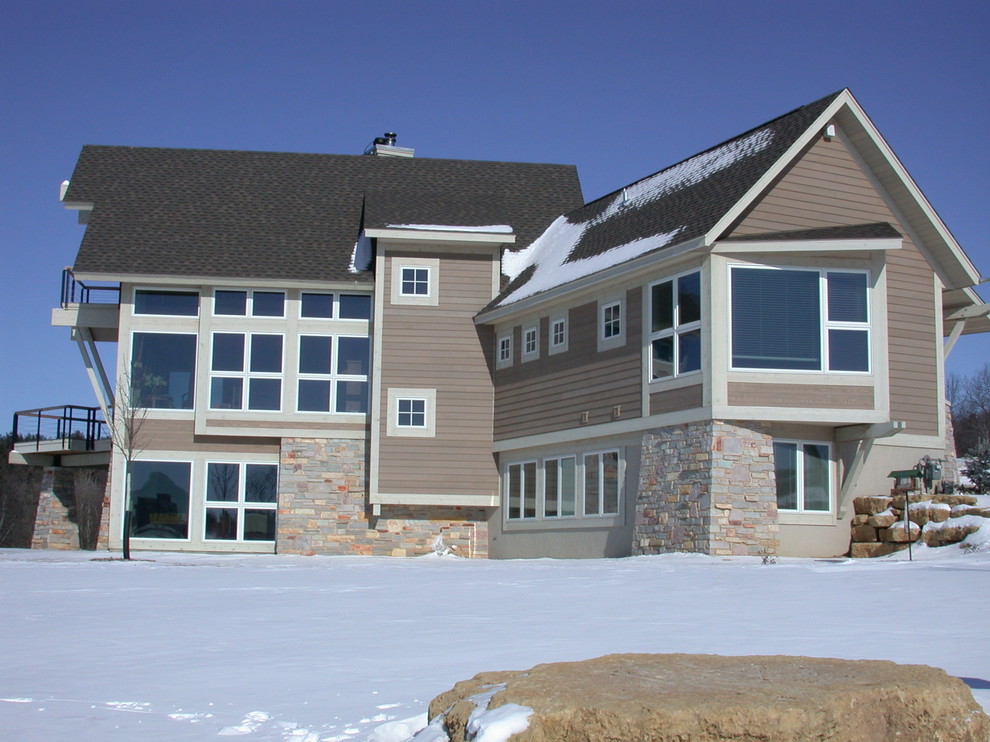 This is an example of a large modern three-storey beige house exterior in Other with mixed siding, a gable roof and a shingle roof.