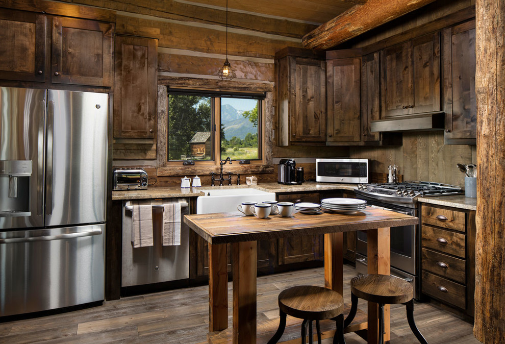 Light wood floor and brown floor open concept kitchen photo with a farmhouse sink, shaker cabinets, dark wood cabinets, marble countertops, wood backsplash, stainless steel appliances, an island and beige countertops
