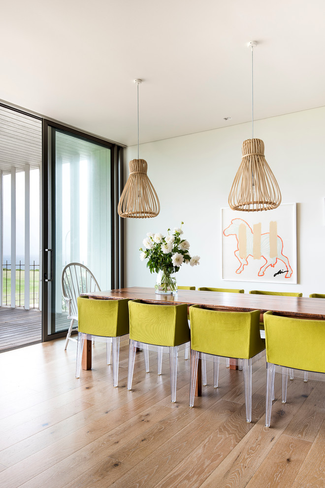 This is an example of a dining room in Sydney with beige walls and light hardwood floors.
