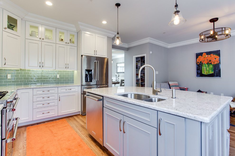 Photo of a mid-sized transitional l-shaped kitchen in Baltimore with an undermount sink, recessed-panel cabinets, white cabinets, quartz benchtops, green splashback, subway tile splashback, stainless steel appliances, medium hardwood floors and with island.