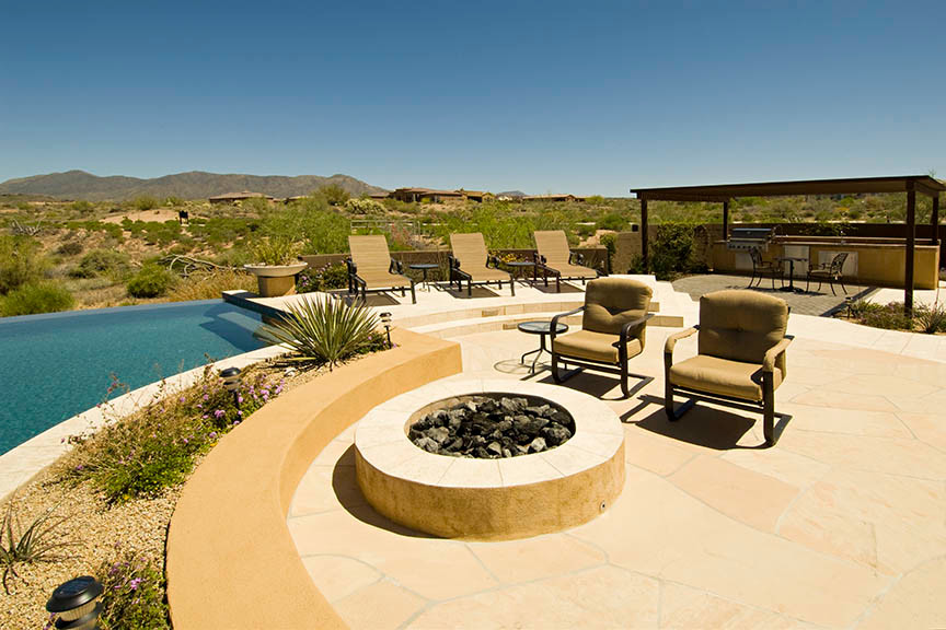 Inspiration for a large backyard custom-shaped infinity pool in Phoenix with natural stone pavers.