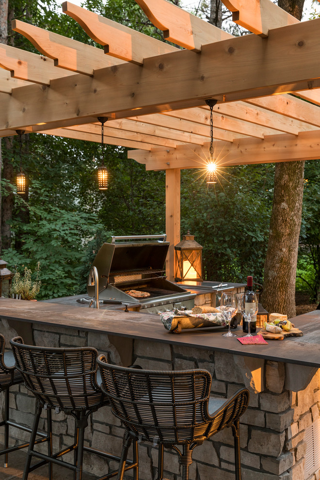 Design ideas for a mid-sized traditional backyard patio in Minneapolis with an outdoor kitchen, natural stone pavers and a pergola.