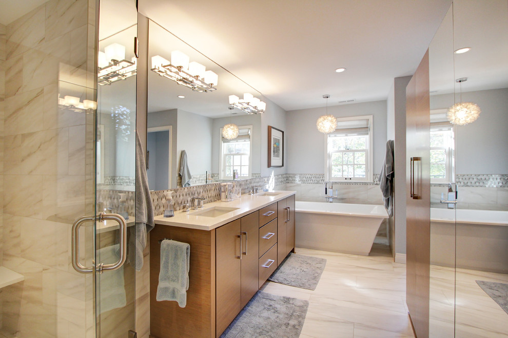 Photo of a mid-sized transitional master bathroom in Denver with flat-panel cabinets, medium wood cabinets, a freestanding tub, beige tile, marble, an undermount sink, solid surface benchtops, a hinged shower door, beige benchtops, a corner shower, grey walls and beige floor.