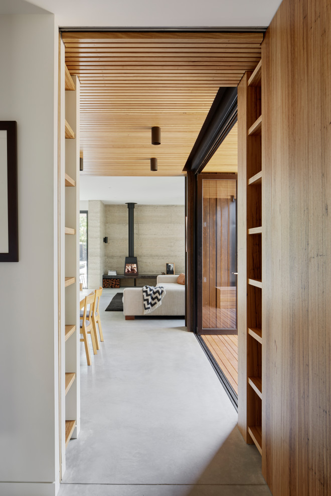 Photo of a mid-sized contemporary hallway in Melbourne with white walls, concrete floors and grey floor.