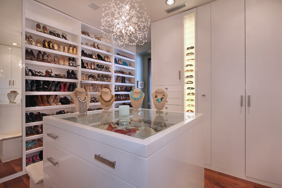Inspiration for a contemporary walk-in wardrobe in Orange County with white cabinets and medium hardwood floors.