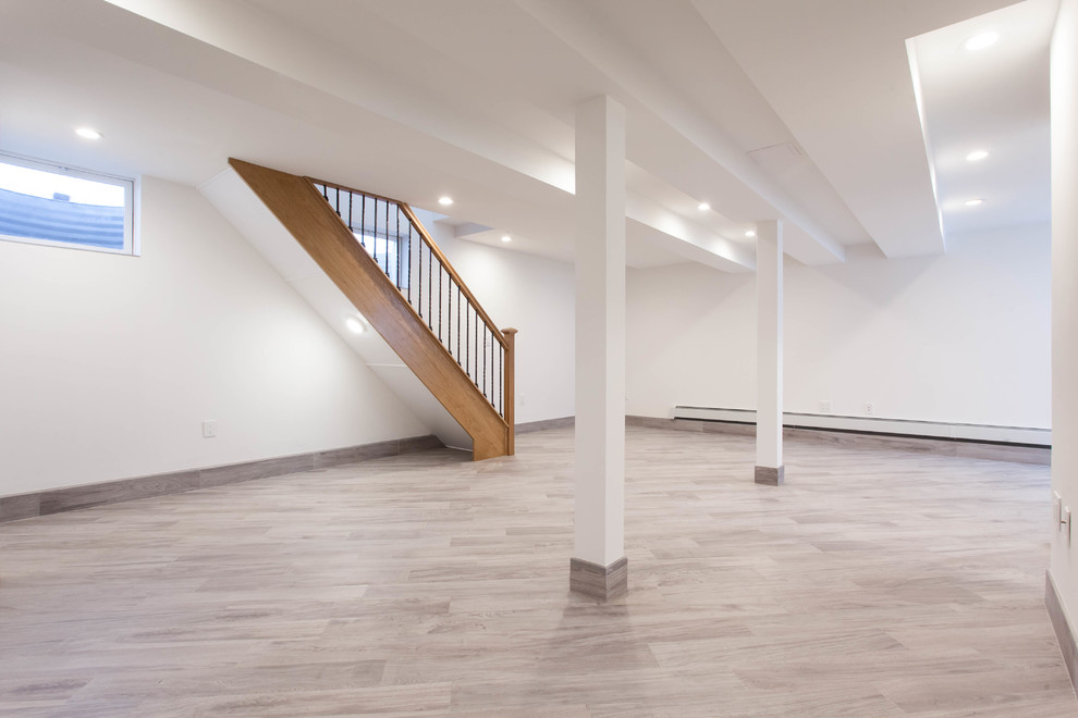 Photo of a large contemporary basement in New York with beige walls, light hardwood floors and brown floor.