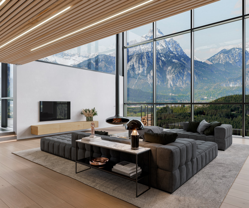 Свежая идея для дизайна: большая двухуровневая гостиная комната в стиле модернизм с телевизором на стене, обоями на стенах, светлым паркетным полом и подвесным камином - отличное фото интерьера