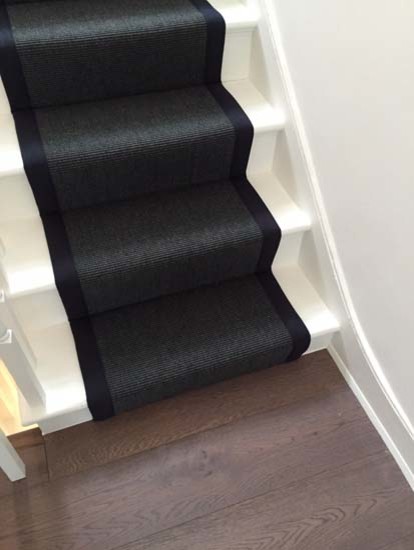 Design ideas for a transitional carpeted u-shaped staircase in London with carpet risers and wood railing.