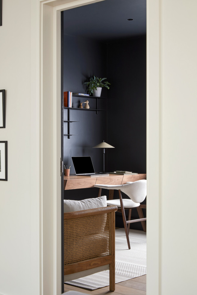 Mid-sized study room in Wiltshire with black walls, medium hardwood floors and a freestanding desk.