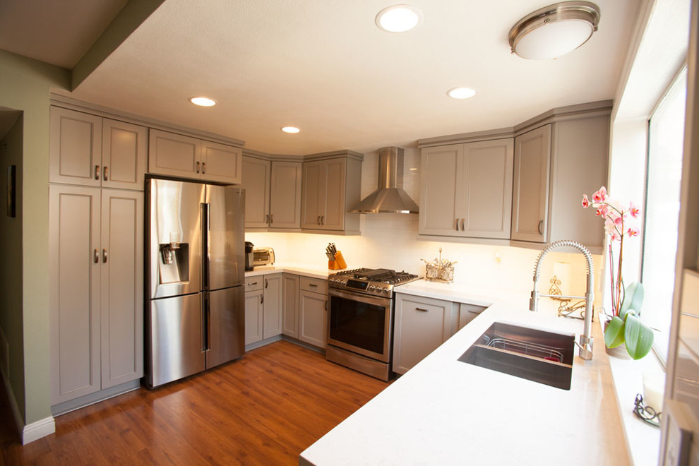 Inspiration for a large transitional u-shaped dark wood floor eat-in kitchen remodel in Los Angeles with an undermount sink, recessed-panel cabinets, gray cabinets, quartz countertops, white backsplash, subway tile backsplash, stainless steel appliances and no island