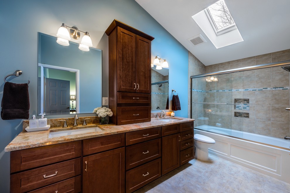 Design ideas for a mid-sized transitional master bathroom in DC Metro with an undermount sink, recessed-panel cabinets, medium wood cabinets, granite benchtops, a drop-in tub, a shower/bathtub combo, a two-piece toilet, beige tile, ceramic tile, blue walls and ceramic floors.