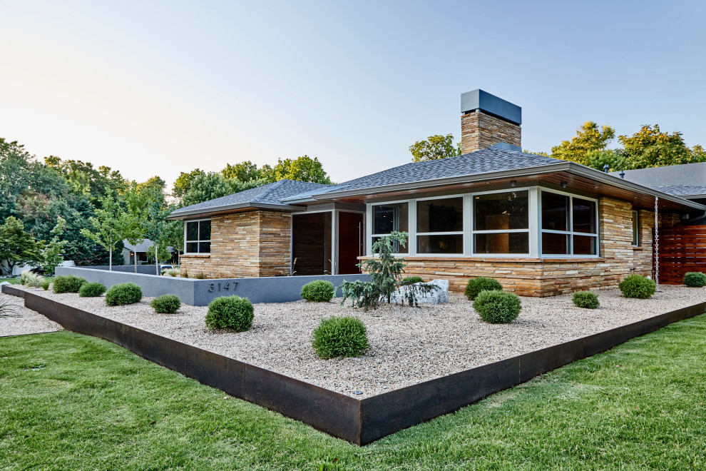 This is an example of a midcentury front yard garden in Other with a retaining wall and gravel.