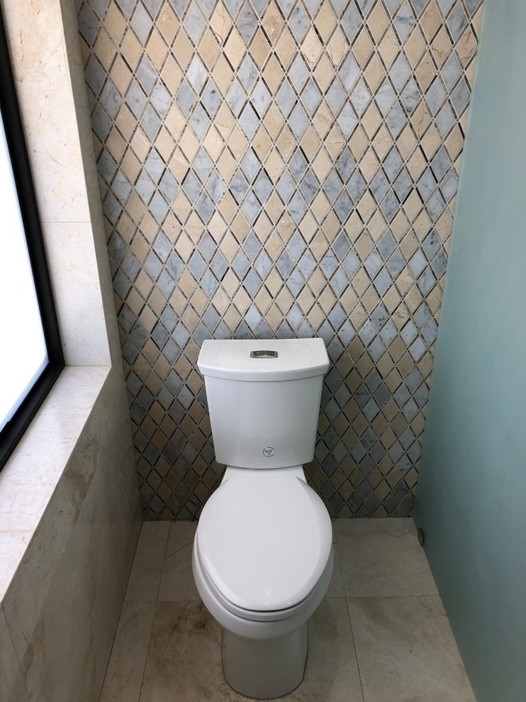 This is an example of a mid-sized contemporary powder room in Miami with flat-panel cabinets, white cabinets, a one-piece toilet, beige tile, marble, yellow walls, marble floors, a pedestal sink, engineered quartz benchtops, beige floor and white benchtops.