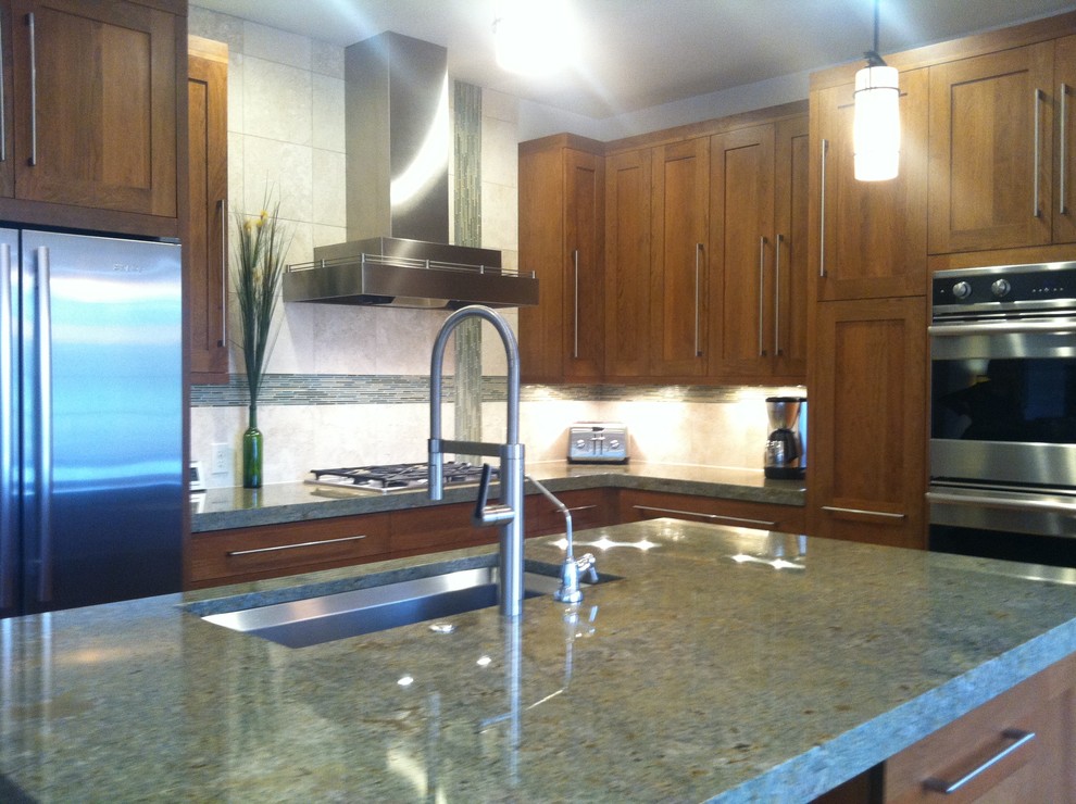Example of a transitional l-shaped eat-in kitchen design in Denver with an undermount sink, shaker cabinets, medium tone wood cabinets, granite countertops, stone tile backsplash and stainless steel appliances
