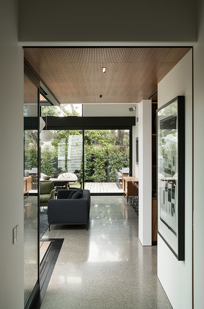 Small midcentury hallway in Auckland with white walls and concrete floors.