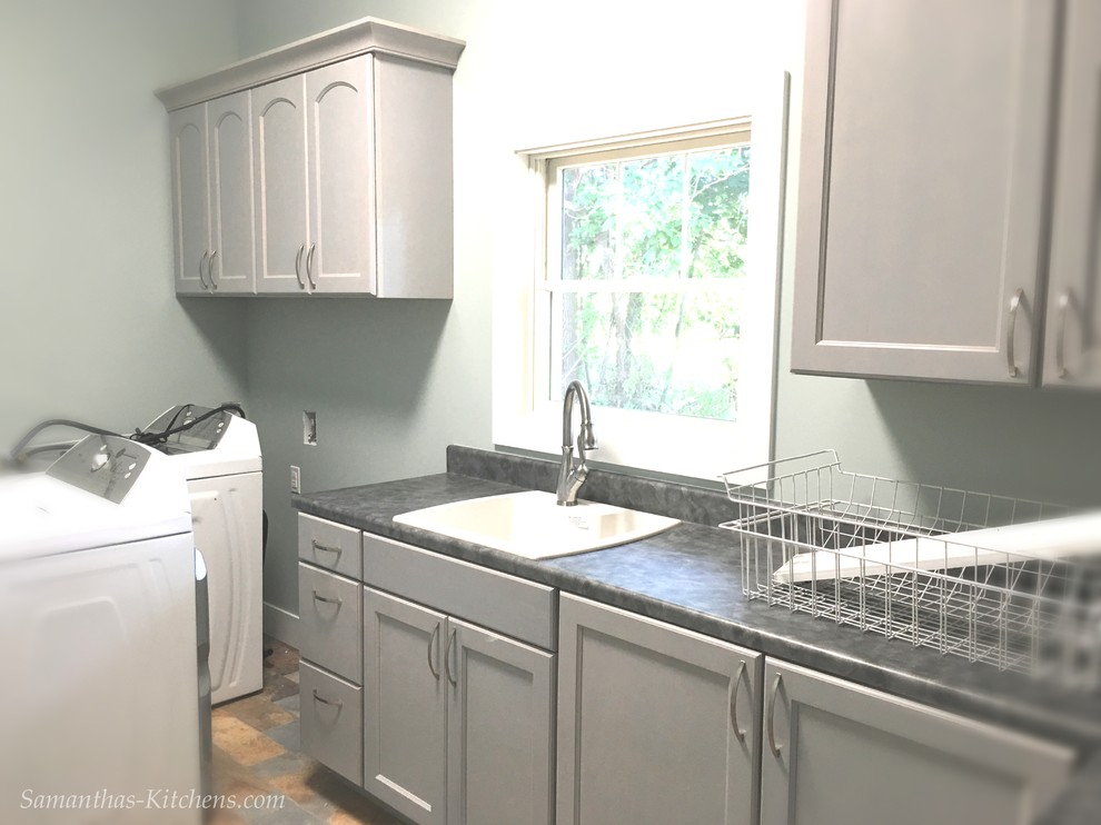 Large transitional l-shaped porcelain tile home design photo with a drop-in sink, recessed-panel cabinets, gray cabinets, laminate countertops, blue walls and a side-by-side washer/dryer