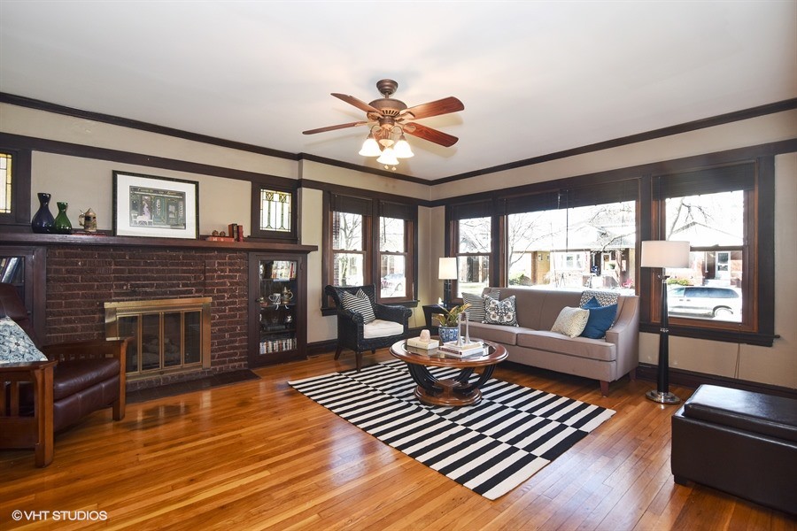 Inspiration for a mid-sized arts and crafts enclosed living room in Chicago with beige walls, medium hardwood floors, a standard fireplace and a brick fireplace surround.