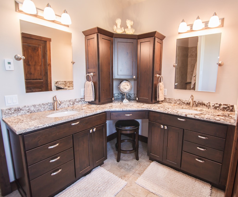 This is an example of a mid-sized traditional master bathroom in Other with flat-panel cabinets, dark wood cabinets, an undermount sink, granite benchtops, a corner shower, a one-piece toilet, beige tile, beige walls, beige floor, a hinged shower door, brown benchtops and ceramic floors.