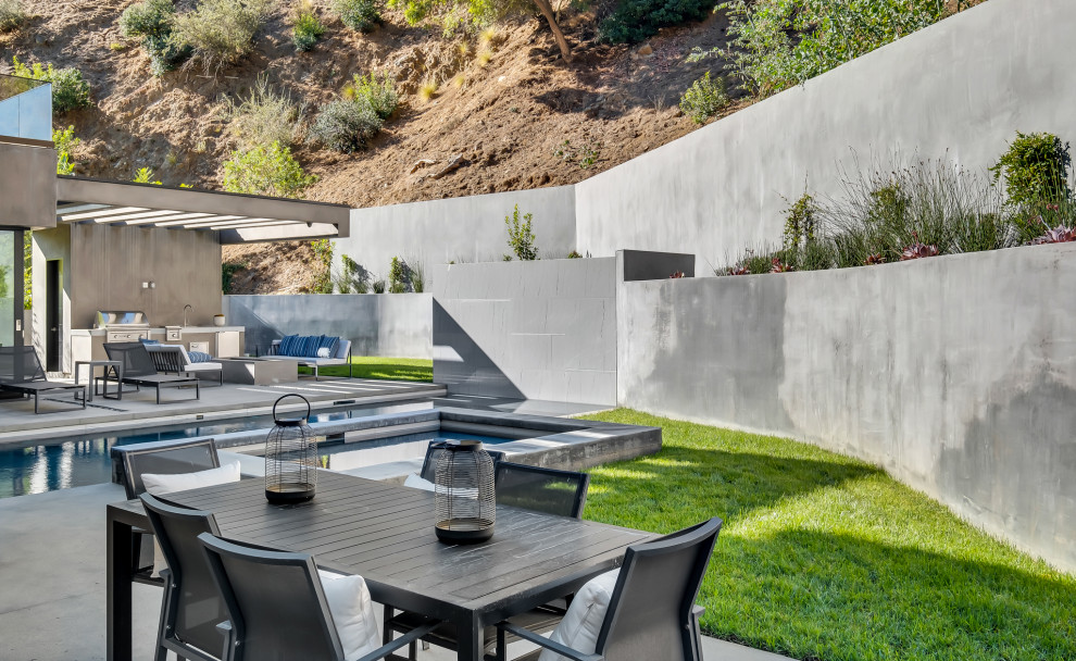 Large modern backyard full sun formal garden in Los Angeles with a retaining wall and concrete pavers.