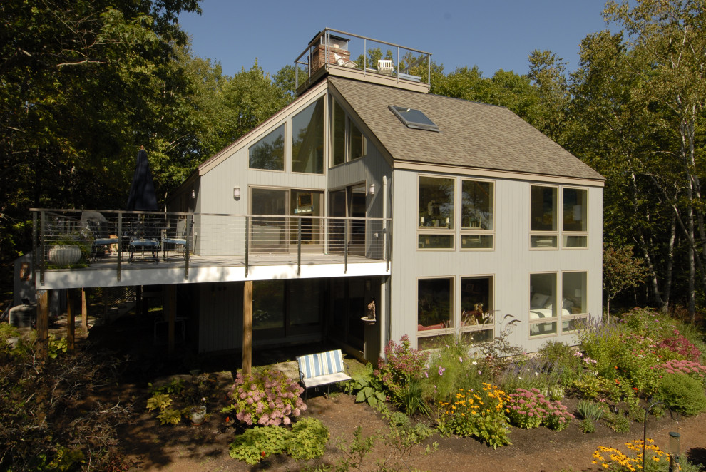 This is an example of a mid-sized modern two-storey beige house exterior in Portland Maine with wood siding, a shed roof and a shingle roof.