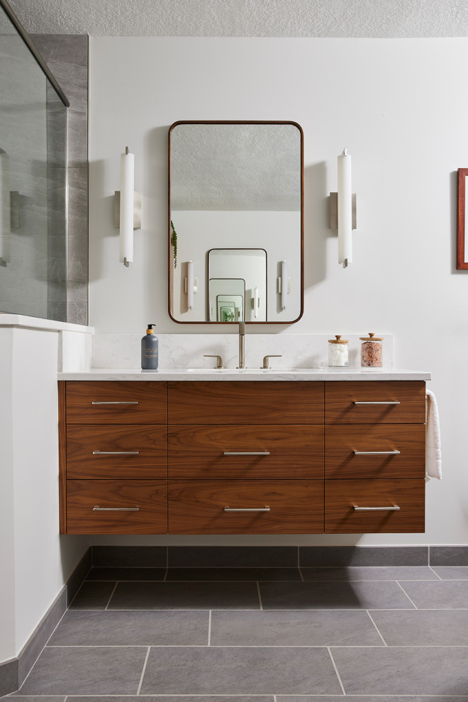 Photo of a large modern bathroom in Minneapolis with flat-panel cabinets, medium wood cabinets, a corner shower, gray tile, porcelain tile, engineered quartz benchtops, white benchtops, a single vanity, a floating vanity, white walls, porcelain floors, an undermount sink, grey floor and a hinged shower door.