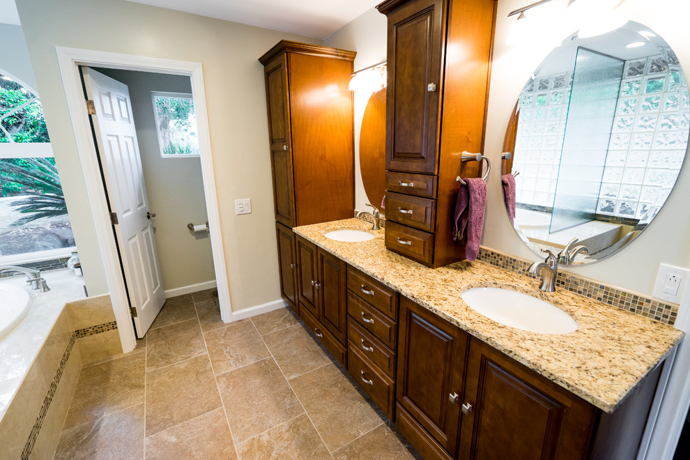 This is an example of a mid-sized modern master bathroom in San Diego with recessed-panel cabinets, light wood cabinets, a corner shower, a two-piece toilet, beige tile, glass tile, beige walls, travertine floors, a drop-in sink and quartzite benchtops.
