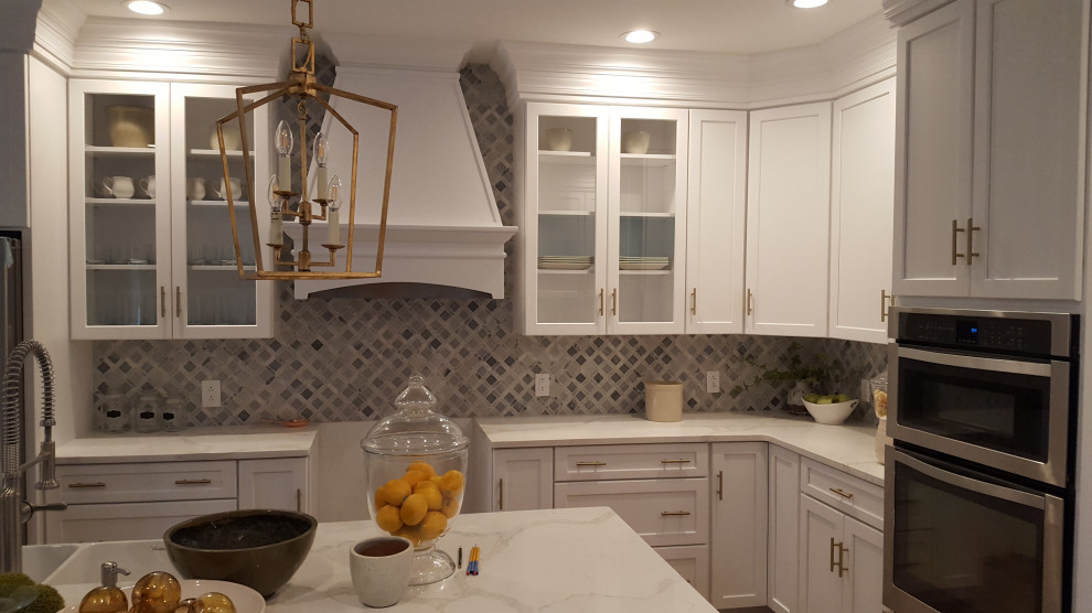 Example of a large transitional u-shaped light wood floor and brown floor eat-in kitchen design in DC Metro with a farmhouse sink, recessed-panel cabinets, white cabinets, quartzite countertops, gray backsplash, marble backsplash, stainless steel appliances, an island and white countertops