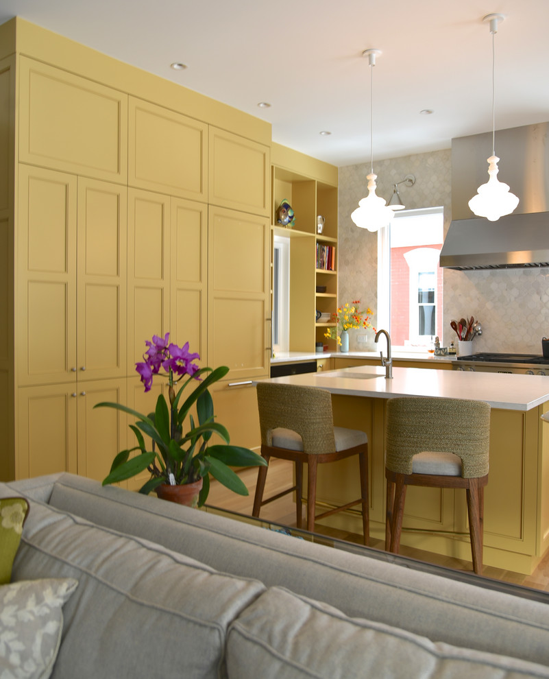 Example of a large transitional u-shaped light wood floor and beige floor open concept kitchen design in Denver with an undermount sink, recessed-panel cabinets, yellow cabinets, quartz countertops, gray backsplash, marble backsplash, paneled appliances, an island and beige countertops