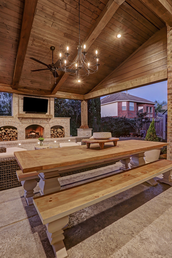 Design ideas for a mid-sized country backyard patio in Houston with with fireplace, concrete slab and a roof extension.