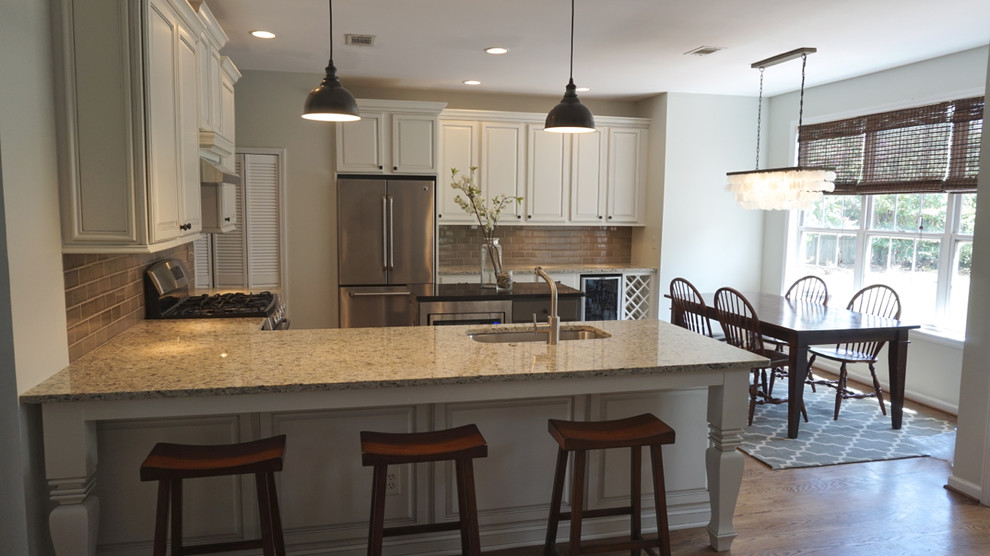 Example of a large transitional u-shaped medium tone wood floor eat-in kitchen design in Atlanta with an undermount sink, raised-panel cabinets, white cabinets, granite countertops, gray backsplash, ceramic backsplash, stainless steel appliances and an island