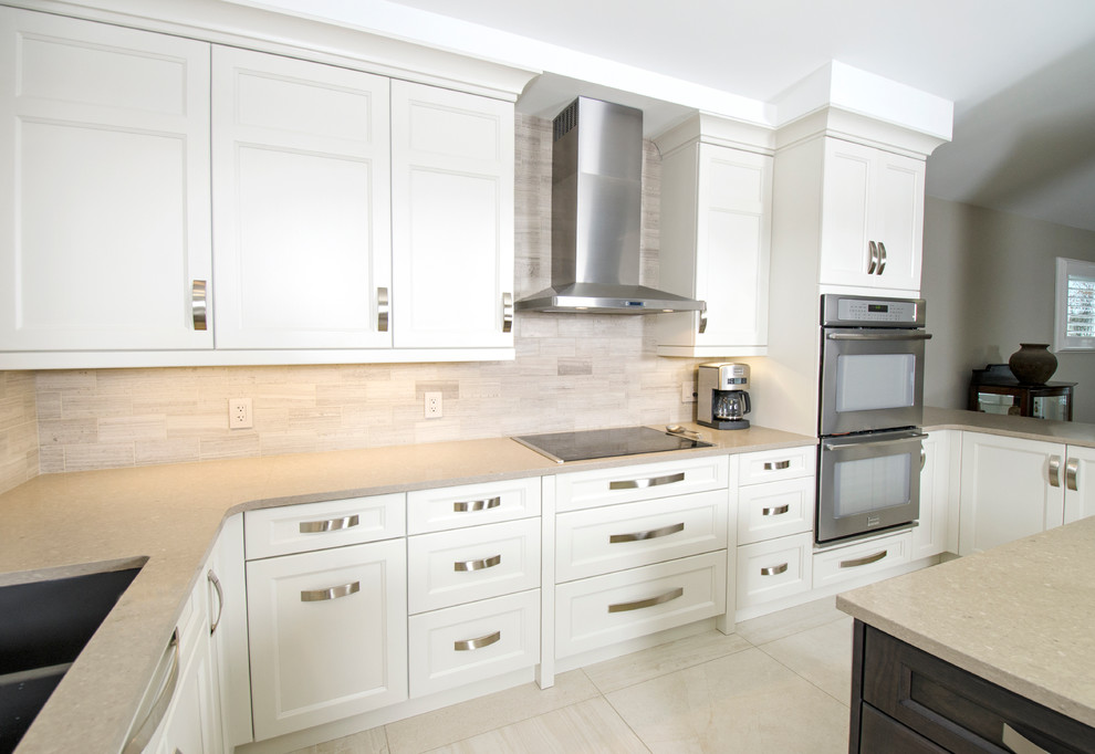Example of a transitional u-shaped limestone floor eat-in kitchen design with an undermount sink, raised-panel cabinets, gray cabinets, quartz countertops, beige backsplash, stone tile backsplash, stainless steel appliances and an island