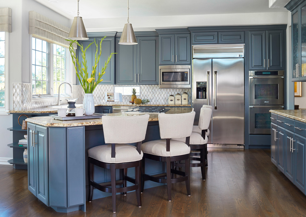 Mid-sized transitional u-shaped medium tone wood floor and brown floor eat-in kitchen photo in Denver with shaker cabinets, blue cabinets, solid surface countertops, white backsplash, glass tile backsplash, stainless steel appliances, an island and beige countertops